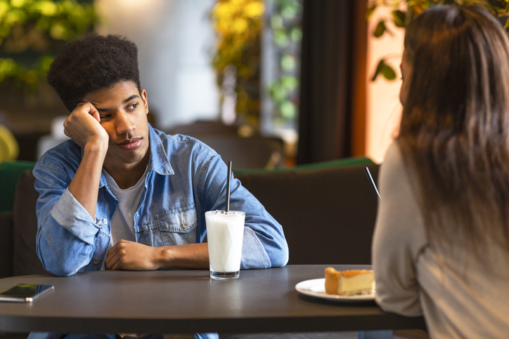 Young boy sat across from a girl looking upset.